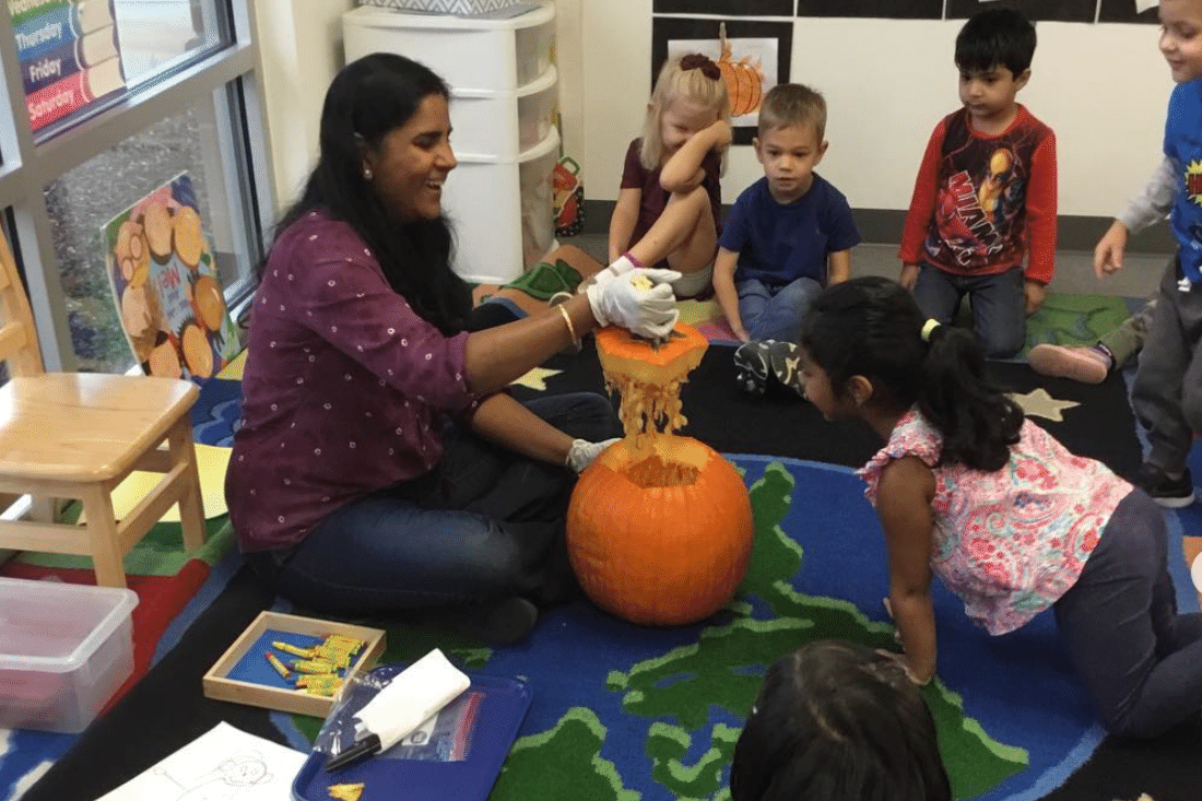 Preschool teacher opening up a pumpkin.