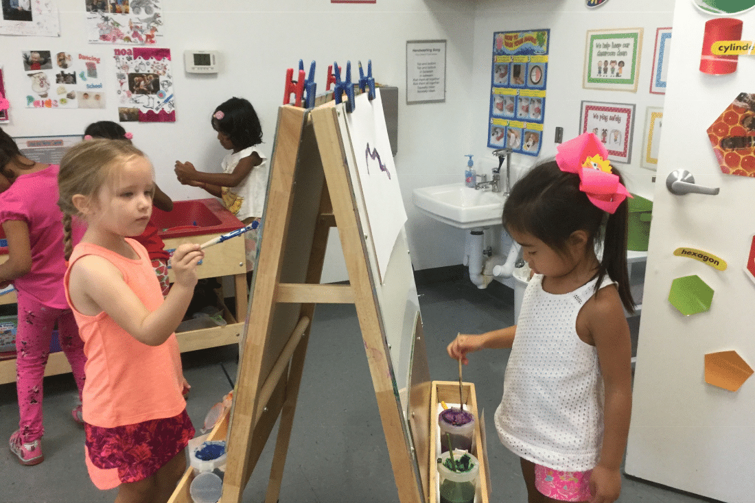 Pre-K students painting at an easel